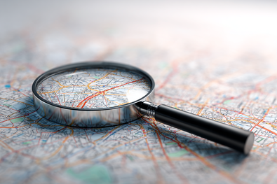 Lupe liegt auf einer Landkarte, als Symbol für Local SEO.