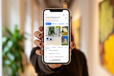 Dame hält ein Smartphone mit einem Google Brancheneintrag am Bildschirm in die Kamera. 